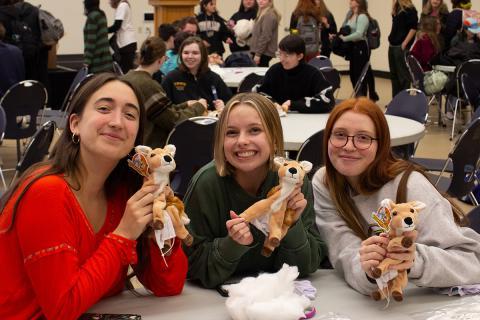 Three students holding up stuffed deer craft.