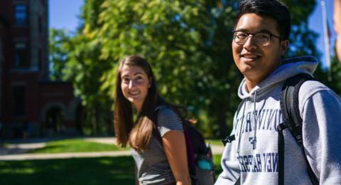 Three students walking and smiling on UNH campus