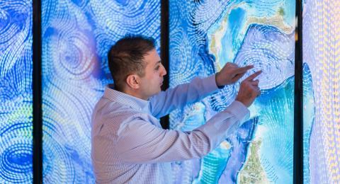 Erol Aygar conducts data visualization research at the Center for Coastal and Ocean Mapping in Durham for his master's thesis using a giant colorful screen wall projection.