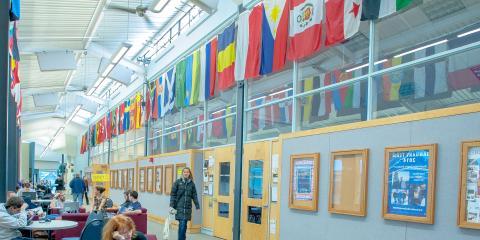 Students studying at tables near international flags hanging on the walls