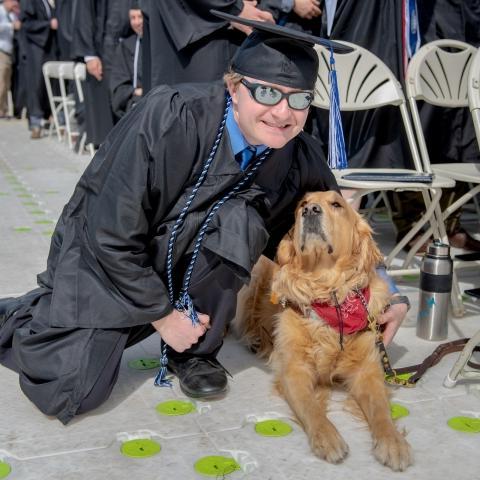 student with service dog at commencement