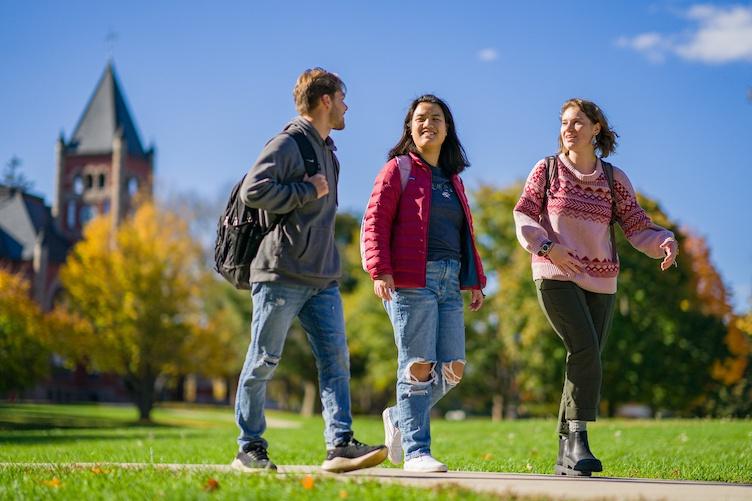 Three students walking on campus with Thompson Hall visible in the background