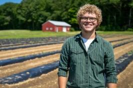 Eliudes Camps Marcano, an exchange student from Puerto Rico, 站在金曼研究农场的一块地里, 去年夏天，他在那里帮助支持联合国大学的农业研究.